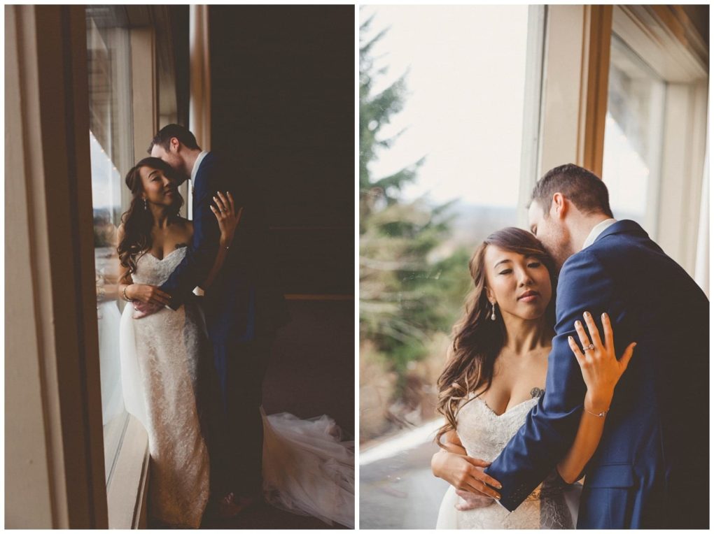Premier snohomish & seattle wedding photographer | gsquared weddings photography a bride in a white gown and a groom in a blue suit embrace by a large window sharing an intimate and tender moment The bride looks peaceful as natural light highlights this beautiful snohomish seattle wedding scene | serving snohomish seattle                   & beyond