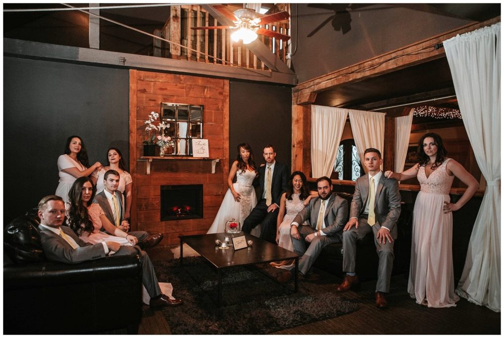 Premier snohomish & seattle wedding photographer | gsquared weddings photography a wedding party of six women in light dresses and five men in gray suits pose together in a stylish rustic living room with a fireplace wooden accents and white curtains capturing relaxed elegance at this snohomish seattle wedding | serving snohomish seattle                   & beyond