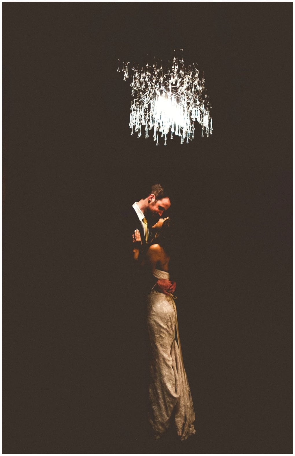 Premier snohomish & seattle wedding photographer | gsquared weddings photography a couple in formal attire embraces and dances under a glowing chandelier at their snohomish seattle wedding engagement surrounded by darkness with light highlighting their figures and creating a romantic atmosphere | serving snohomish seattle                   & beyond