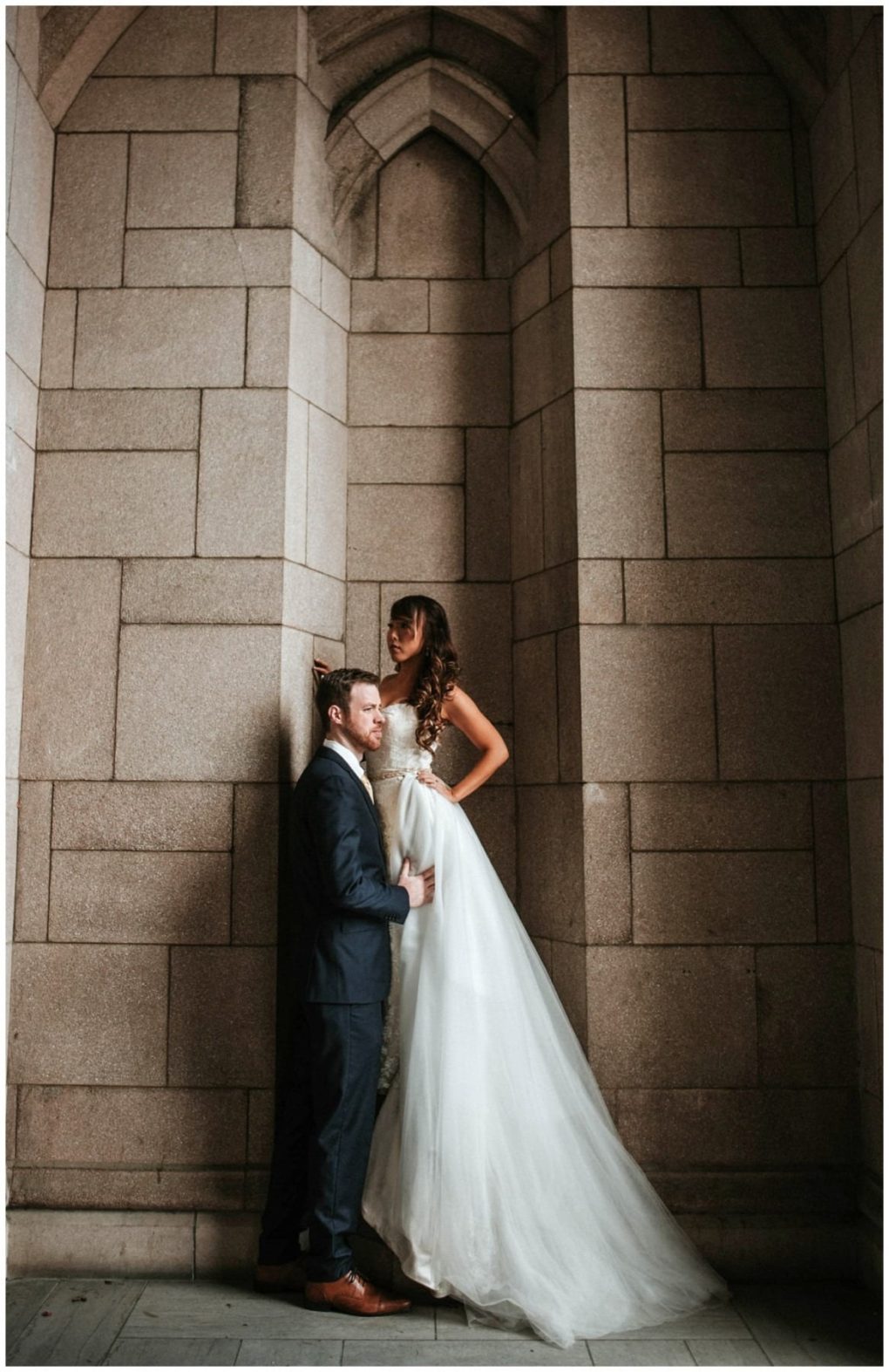 Premier snohomish & seattle wedding photographer | gsquared weddings photography a bride in a white gown stands on a ledge against a stone wall looking down at a groom in a dark suit who gently holds her waist inside an arched alcove during their romantic snohomish seattle wedding | serving snohomish seattle                   & beyond