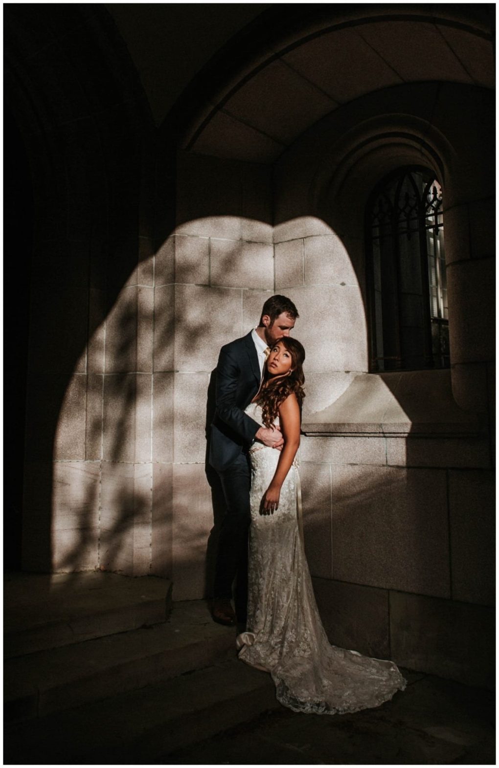 Premier snohomish & seattle wedding photographer | gsquared weddings photography a bride in a white lace gown and a groom in a dark suit stand closely together in dramatic lighting by a stone archway with shadows and sunlight highlighting this unforgettable snohomish seattle wedding moment | serving snohomish seattle                   & beyond