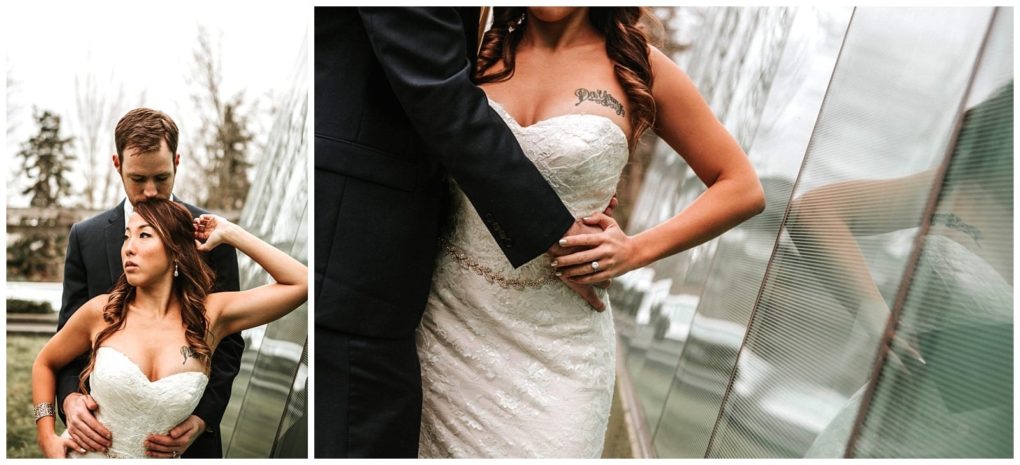 Premier snohomish & seattle wedding photographer | gsquared weddings photography a bride in a strapless white lace gown stands beside a modern glass structure at a snohomish seattle wedding with a groom in a dark suit closely behind her holding her waist as she poses with one arm raised | serving snohomish seattle                   & beyond