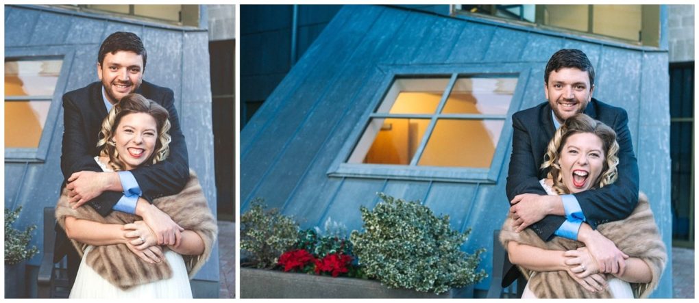 Premier snohomish & seattle wedding photographer | gsquared weddings photography a man in a suit hugs a smiling woman in a fur shawl from behind both pose in front of a modern building with a large slanted window and potted plants capturing their snohomish seattle engagement | serving snohomish seattle                   & beyond
