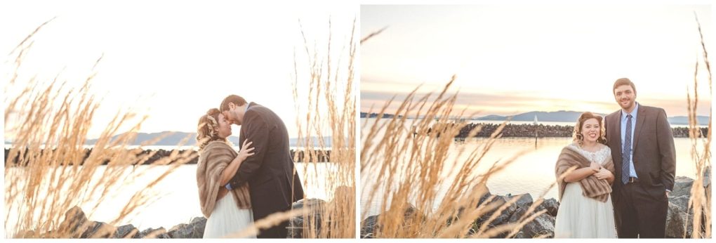 Premier snohomish & seattle wedding photographer | gsquared weddings photography a couple dressed formally stands by a lakeside at sunset surrounded by tall dry grass and rocks In these snohomish seattle engagement photos they share a kiss and smile at the camera with mountains and calm water in the background | serving snohomish seattle                   & beyond