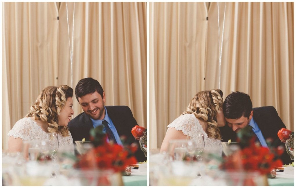 Premier snohomish & seattle wedding photographer | gsquared weddings photography two people in formal attire sit close together at a table smiling and sharing an intimate joyful moment during their snohomish wedding engagement The background features tan curtains with blurred glasses and red flowers in the foreground | serving snohomish seattle                   & beyond