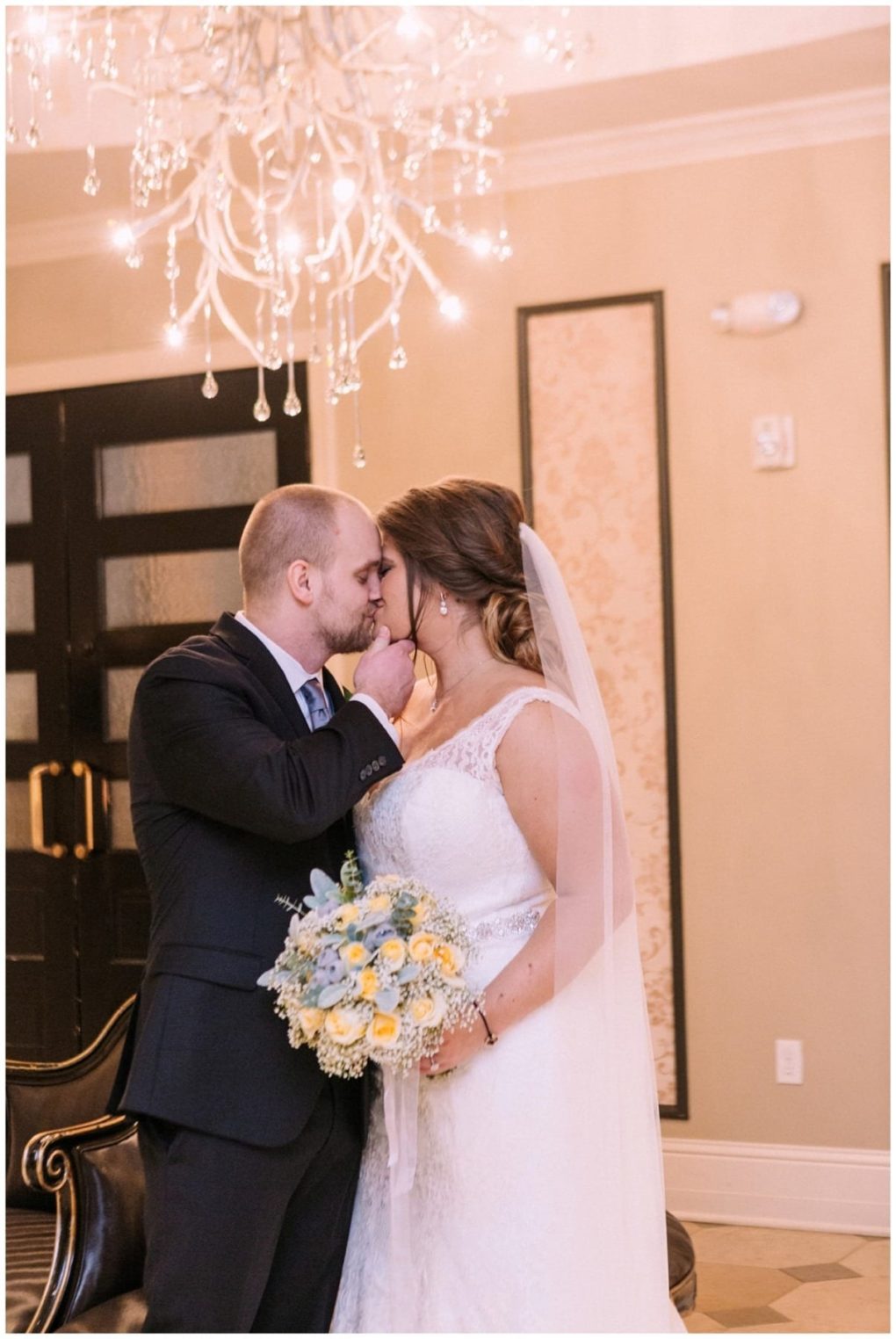 Premier snohomish & seattle wedding photographer | gsquared weddings photography a bride and groom stand closely touching foreheads and smiling under a chandelier during their snohomish wedding The bride holds a bouquet of yellow and white flowers the groom wears a black suit for this special seattle engagement | serving snohomish seattle                   & beyond