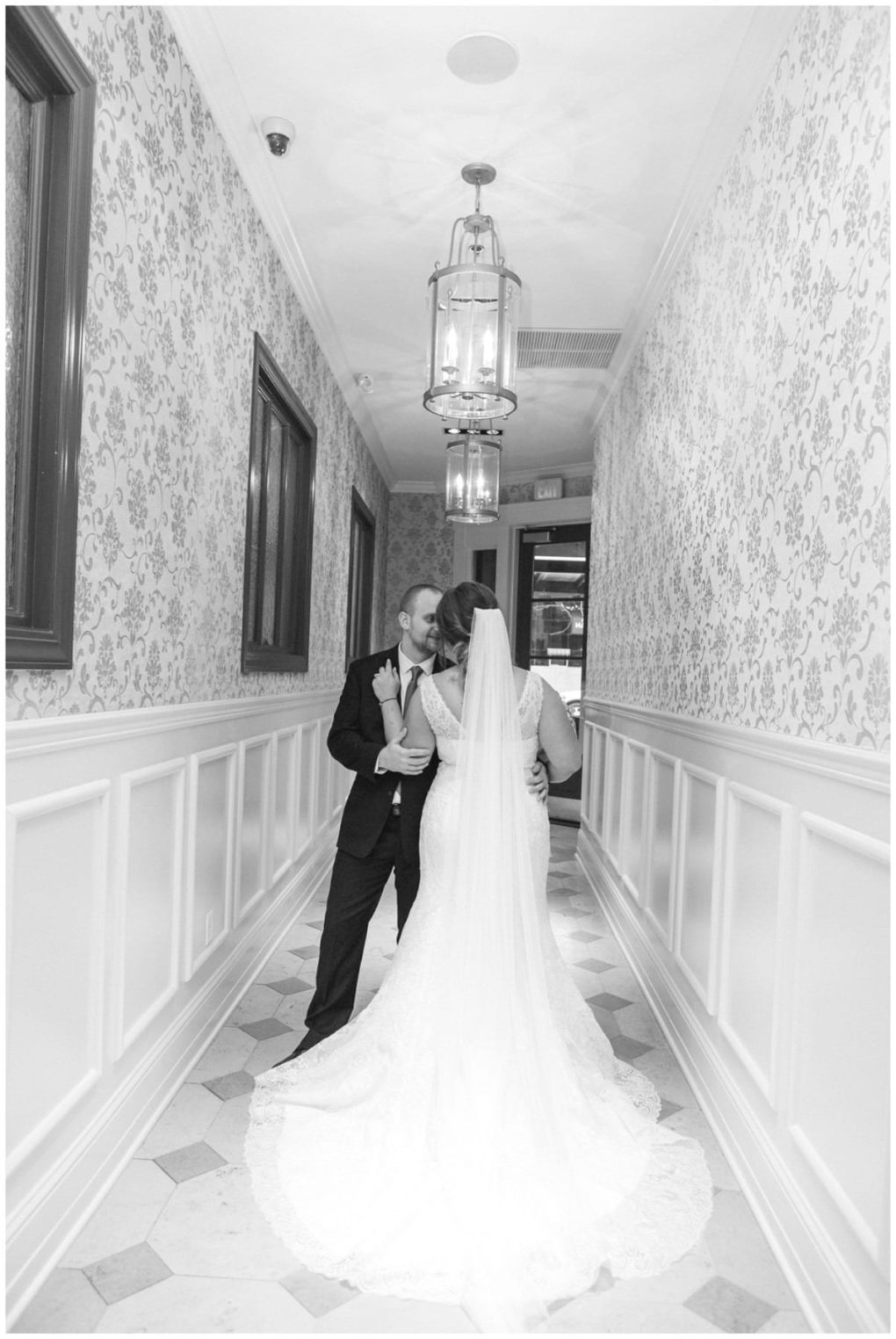 Premier snohomish & seattle wedding photographer | gsquared weddings photography a snohomish bride and groom share an intimate moment in a hallway lined with patterned wallpaper and elegant light fixtures the bride in a flowing gown with a veil facing her groomcapturing the essence of a seattle wedding engagement | serving snohomish seattle                   & beyond