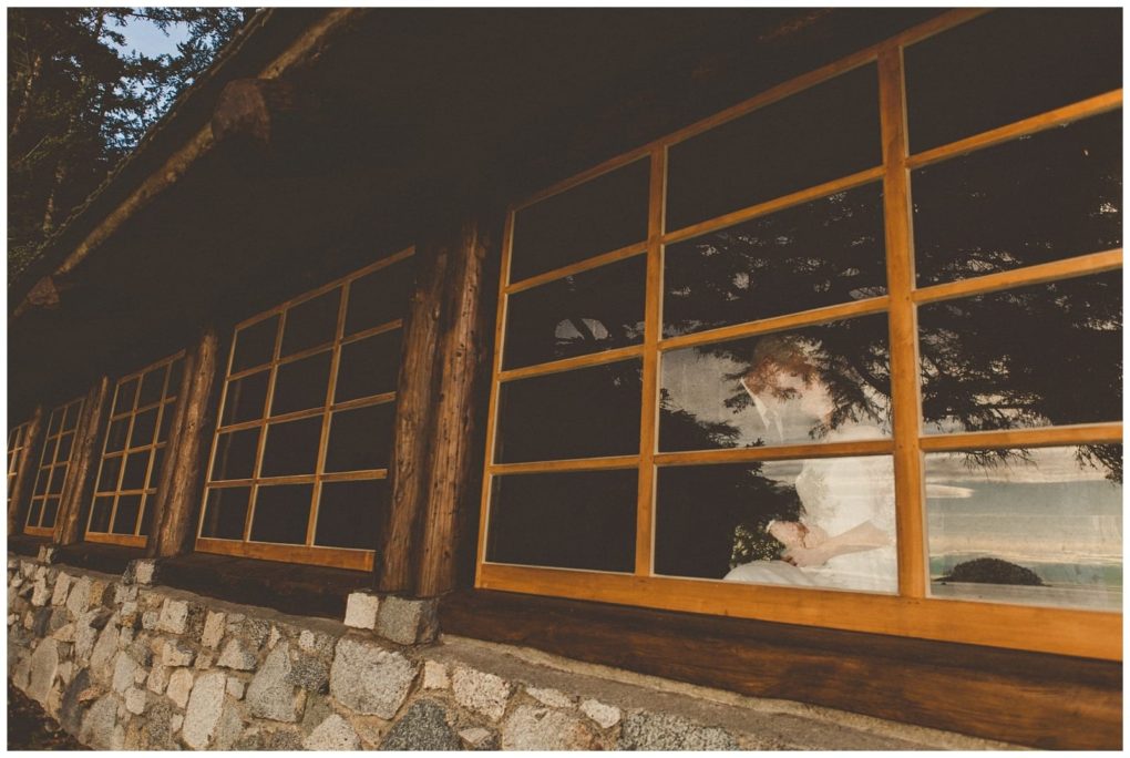 Premier snohomish & seattle wedding photographer | gsquared weddings photography a bride in a white dress sits inside a rustic stone and wood building near snohomish her reflection blending with trees and sky outsidea dreamy seattle wedding scene | serving snohomish seattle                   & beyond