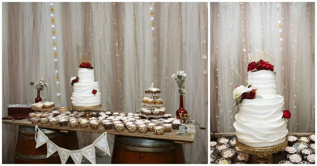 Premier snohomish & seattle wedding photographer | gsquared weddings photography a rustic snohomish wedding dessert table features a three tier white cake with red and white flowers cupcakes in gold wrappers a love banner and string lights draped across a wooden plank supported by barrels | serving snohomish seattle                   & beyond