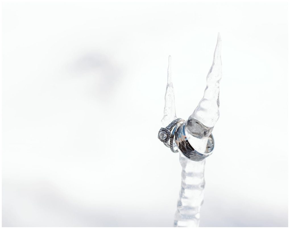 Premier snohomish & seattle wedding photographer | gsquared weddings photography a pair of silver wedding rings one with a diamond are balanced on the tip of a clear icicle against a bright snowy white backgroundcapturing the magic of a snohomish seattle wedding engagement | serving snohomish seattle                   & beyond