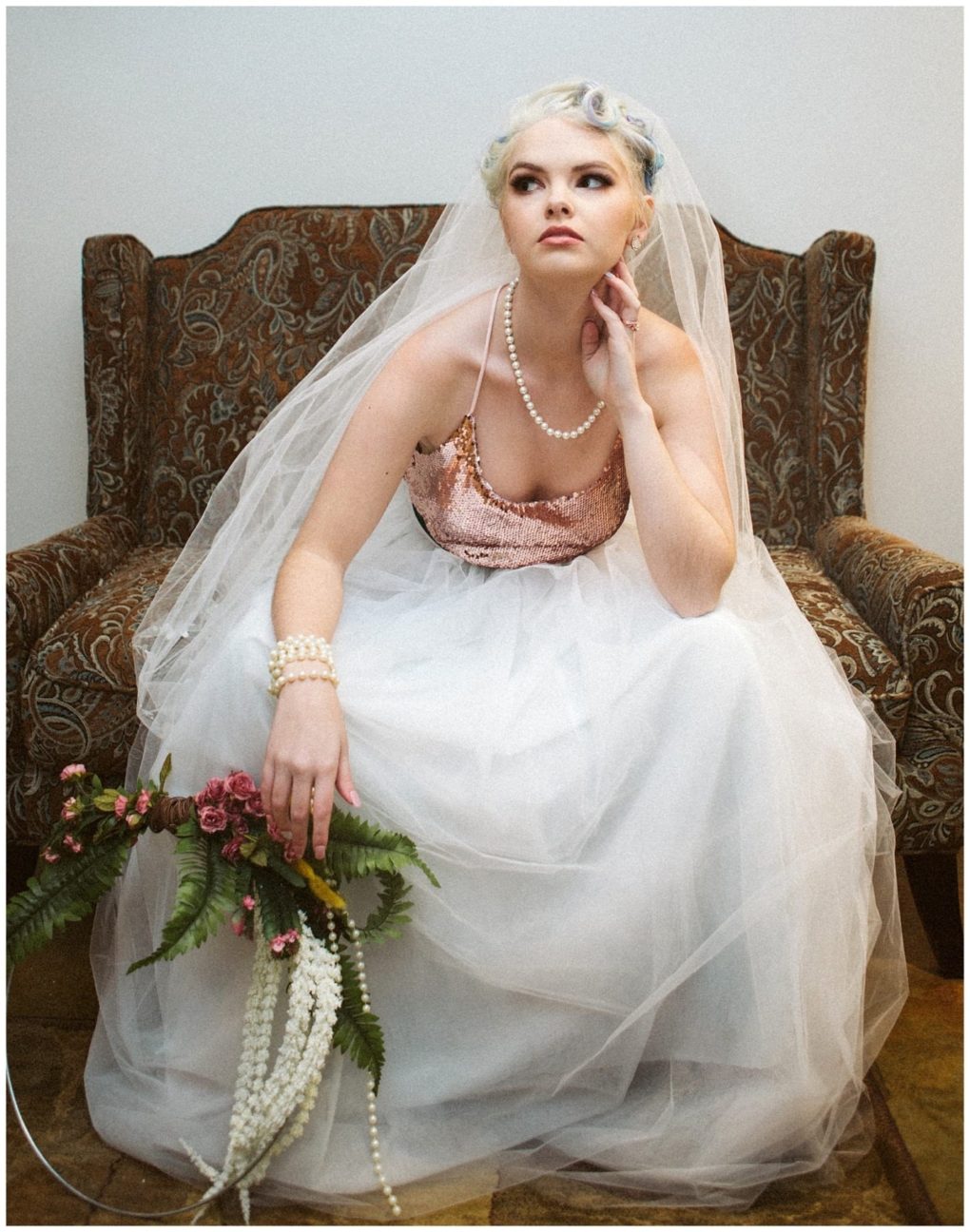Premier snohomish & seattle wedding photographer | gsquared weddings photography a bride in a white tulle dress with a sparkly pink bodice and pearl jewelry sits on a patterned chair holding a floral bouquet and gazing upward thoughtfully at her snohomish seattle wedding engagement | serving snohomish seattle                   & beyond