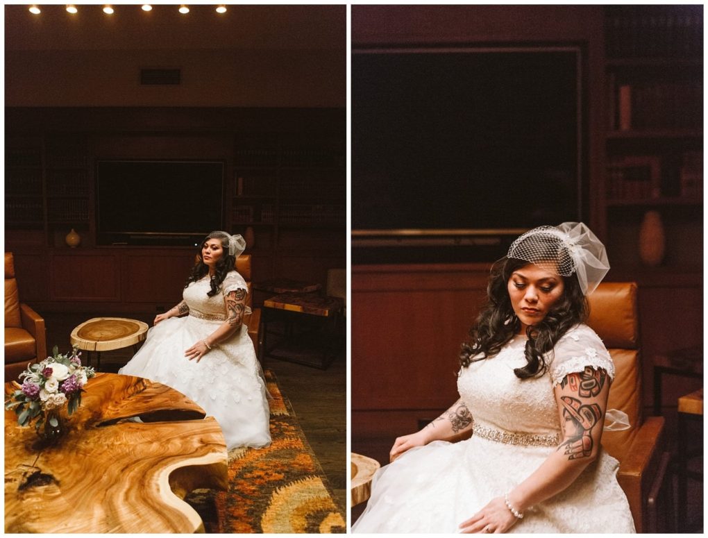 Premier snohomish & seattle wedding photographer | gsquared weddings photography a bride with long dark hair a veil and visible arm tattoos sits in a wood paneled room near snohomish wearing a white wedding dress and looking down thoughtfully her bouquet rests on a wooden table nearby | serving snohomish seattle                   & beyond