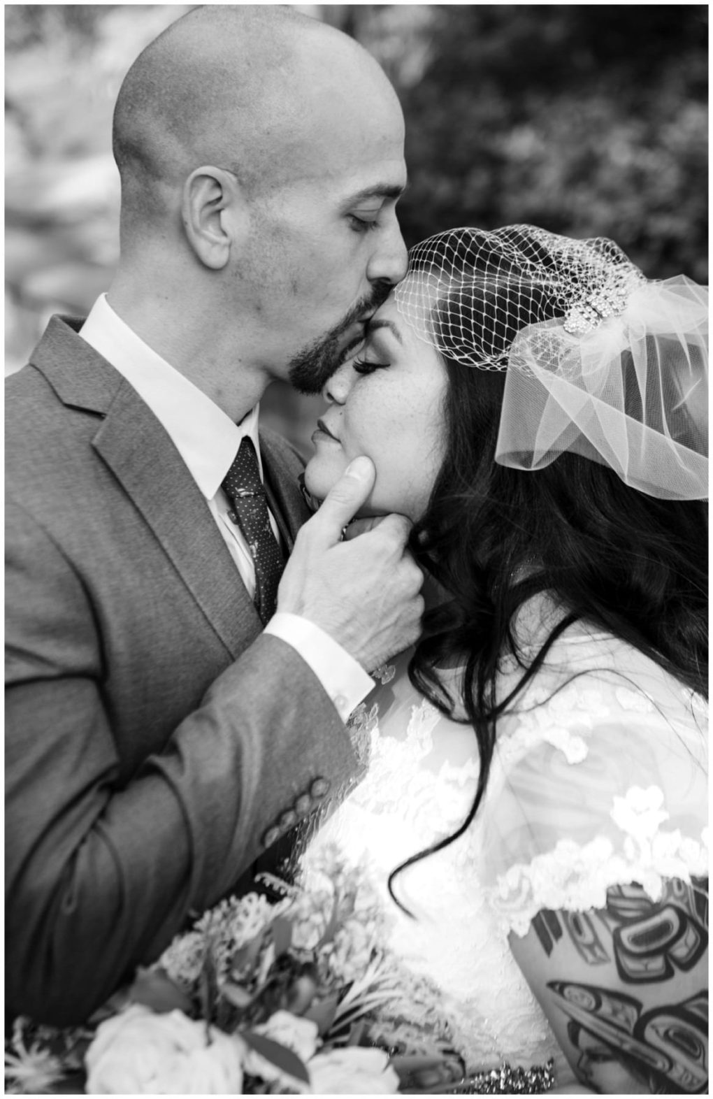 Premier snohomish & seattle wedding photographer | gsquared weddings photography a groom gently kisses his brides forehead as they embrace in soft natural light her lace dress and birdcage veil glowing Captured outdoors near snohomish this black and white photo radiates seattle wedding engagement romance | serving snohomish seattle                   & beyond