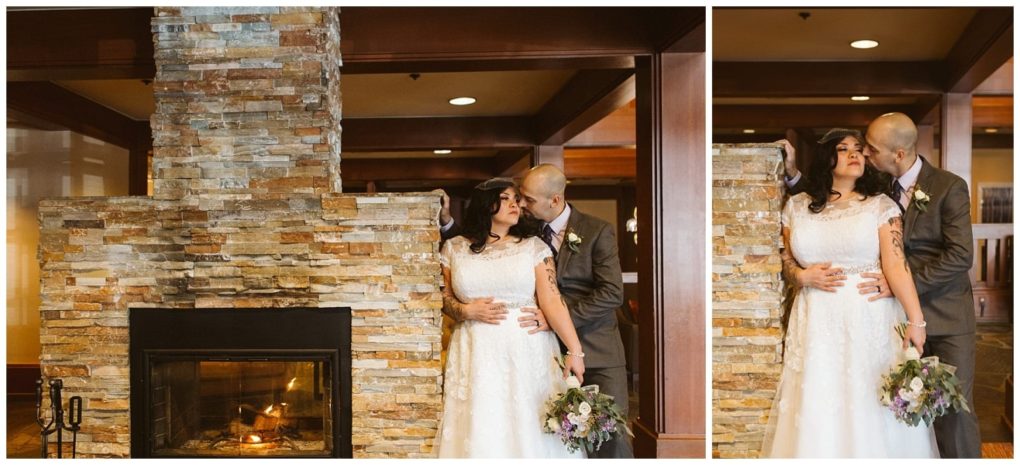 Premier snohomish & seattle wedding photographer | gsquared weddings photography a bride in a white lace dress holding a bouquet stands with her groom in a suit beside a stone fireplace They embrace and gaze at each other smiling in a warmly lit room during their snohomish wedding | serving snohomish seattle                   & beyond