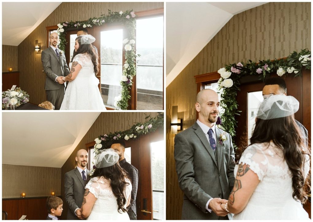 Premier snohomish & seattle wedding photographer | gsquared weddings photography a couple stands facing each other holding hands and smiling during a snohomish wedding ceremony near seattle A floral arch decorates the space behind them while a child sits nearby | serving snohomish seattle                   & beyond