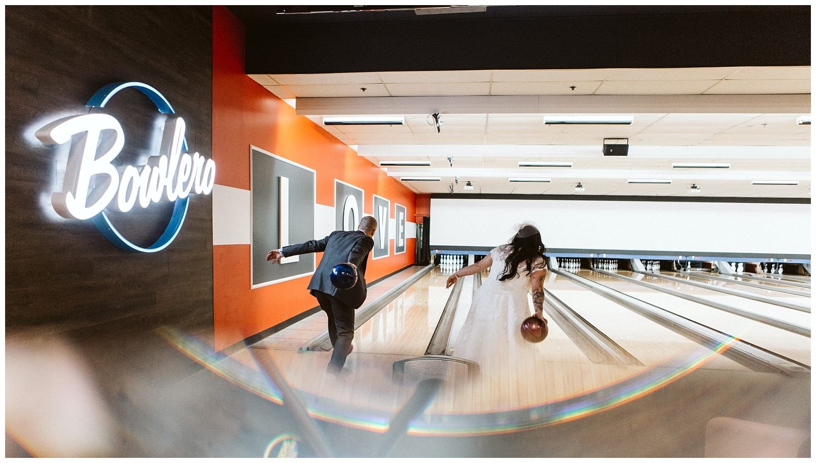 Premier Snohomish & Seattle Wedding Photographer | GSquared Weddings Photography A bride and groom in wedding attire bowl side by side at a modern bowling alley near Snohomish Seattle. The groom sports a suit, the bride a white dress and veil, with Bowlero lit up on the wall—a fun twist on their wedding engagement.                                   | Serving Snohomish, Seattle ,                  & Beyond