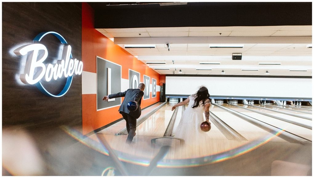 Premier snohomish & seattle wedding photographer | gsquared weddings photography a bride and groom dressed in wedding attire bowl side by side at a modern snohomish seattle wedding venue with a neon bowlero sign and several colorful lanes visible | serving snohomish seattle                   & beyond