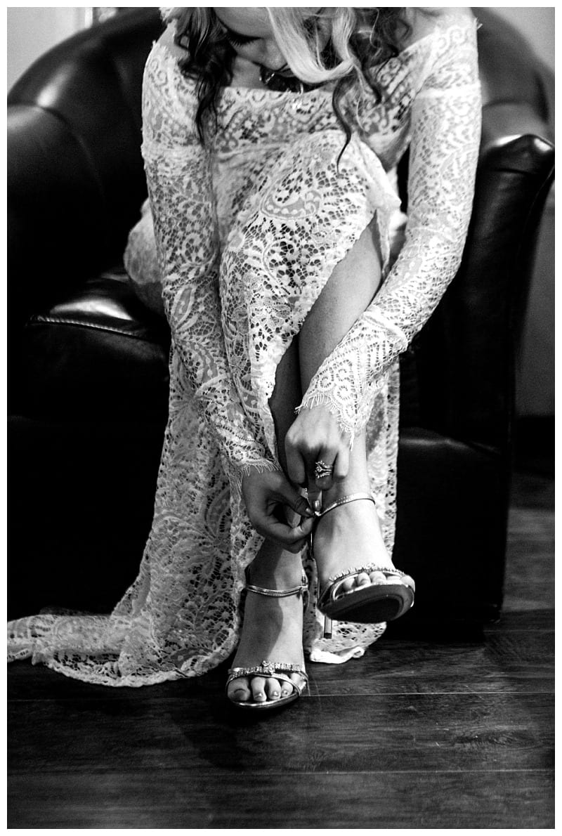 Premier snohomish & seattle wedding photographer | gsquared weddings photography a woman in a lace wedding dress sits on a dark leather chair bending forward to fasten the strap of her high heeled sandal Captured in black and white this intimate moment reflects the elegance of a snohomish seattle wedding | serving snohomish seattle                   & beyond