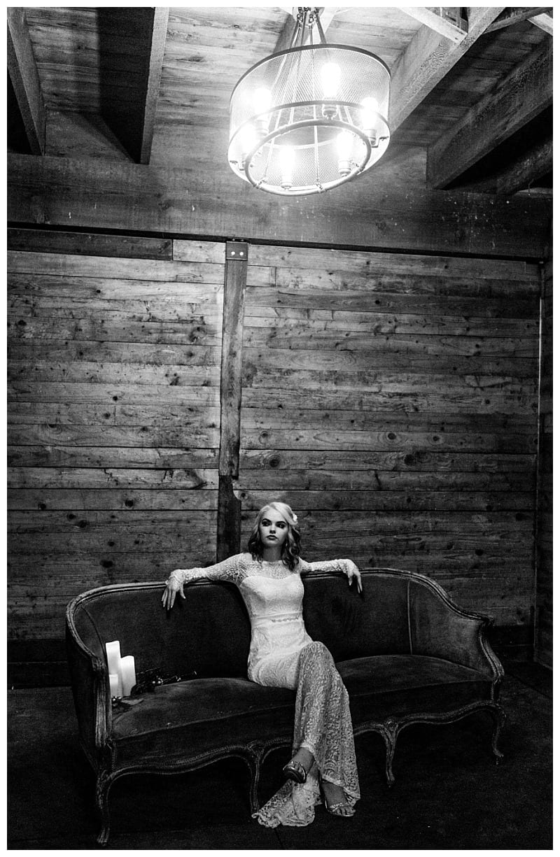 Premier snohomish & seattle wedding photographer | gsquared weddings photography a woman in a long lace dress sits on a vintage sofa in a rustic wooden room under a chandeliercapturing timeless snohomish wedding stylein this black and white portrait | serving snohomish seattle                   & beyond