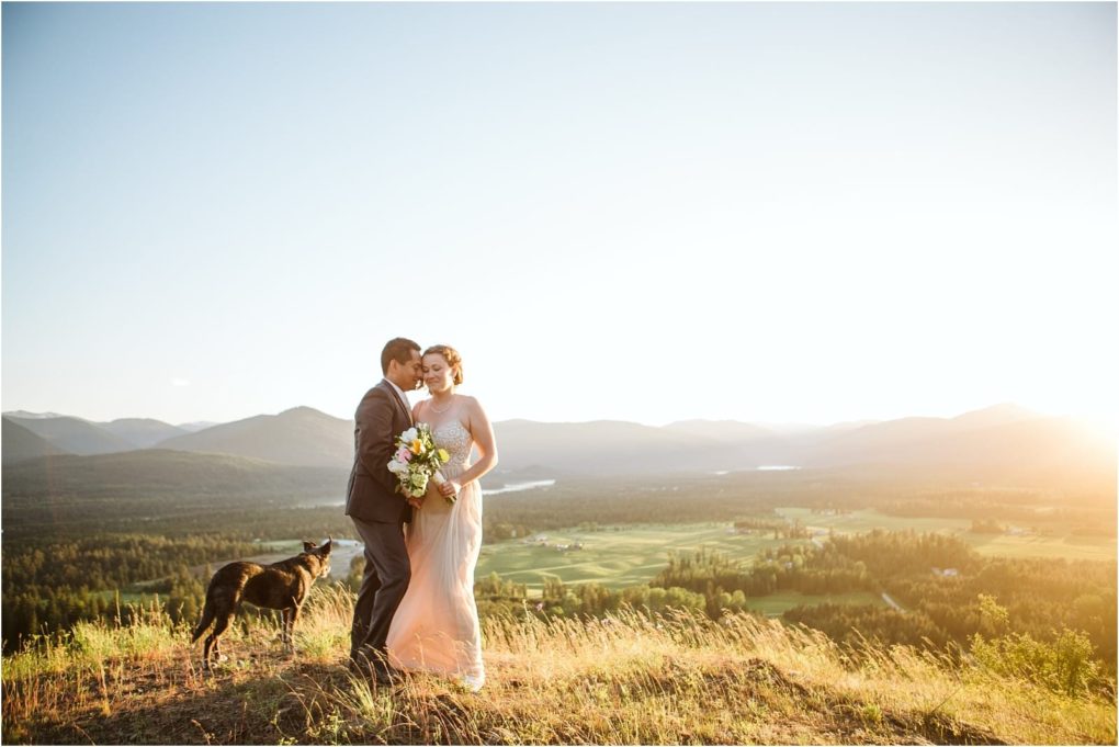 Premier snohomish & seattle wedding photographer | gsquared weddings photography a bride and groom stand on a hilltop at sunset embracing and holding a bouquet with their dog nearby The snohomish landscape below features green fields forests and distant mountains under a bright seattle sky | serving snohomish seattle                   & beyond
