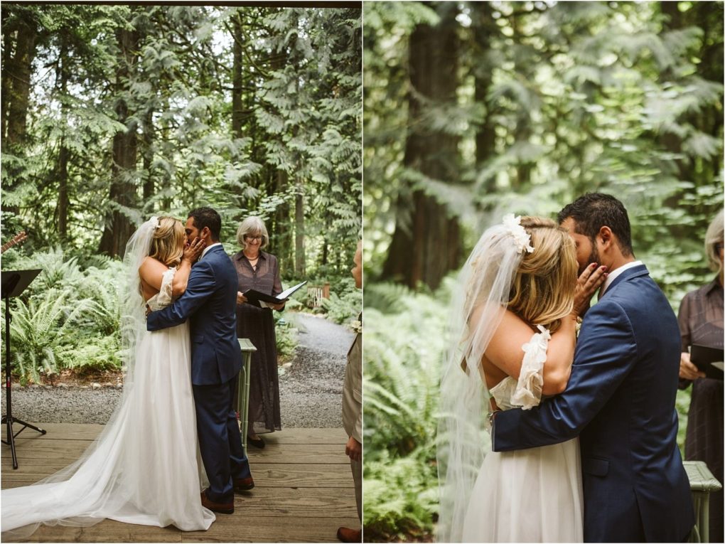Premier snohomish & seattle wedding photographer | gsquared weddings photography a bride and groom share a kiss during their outdoor snohomish wedding ceremony in a lush green forest The bride wears a white dress and veil and the groom wears a blue suit as the officiant stands behind them holding a book | serving snohomish seattle                   & beyond