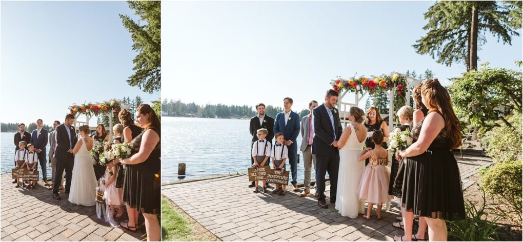 Premier snohomish & seattle wedding photographer | gsquared weddings photography a snohomish lakeside wedding ceremony with the bride and groom under a floral arch their wedding party nearby and children holding a wooden signall beneath clear blue skies capturing the essence of seattle wedding engagement magic | serving snohomish seattle                   & beyond