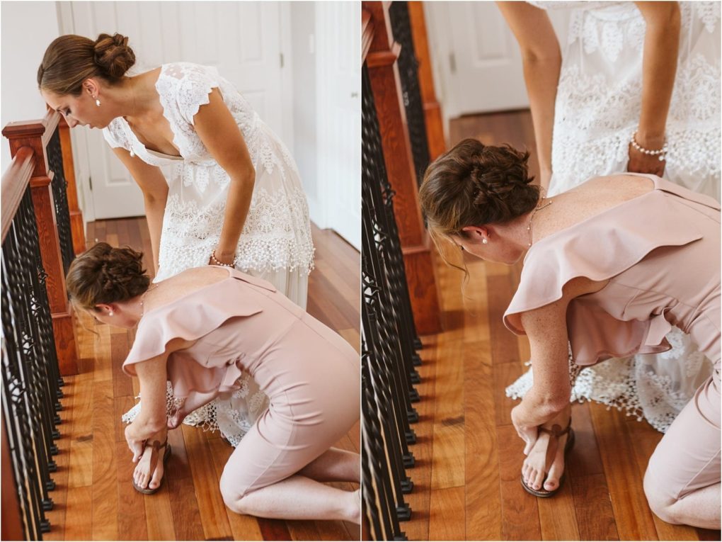 Premier snohomish & seattle wedding photographer | gsquared weddings photography a woman in a blush pink dress kneels on a wooden floor to help a bride in a white lace gown put on her shoes This sweet snohomish seattle wedding moment unfolds at the top of a staircase with an elegant black railing | serving snohomish seattle                   & beyond