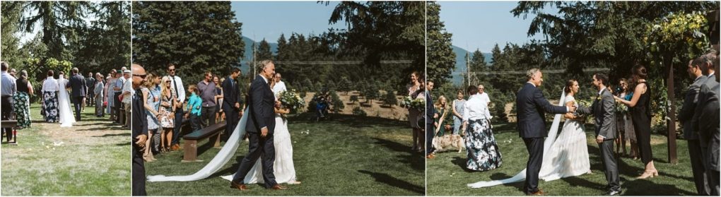 Premier snohomish & seattle wedding photographer | gsquared weddings photography a bride in a white dress walks down an outdoor aisle with her escort surrounded by standing guests on a sunny day amid trees and mountainscapturing the magic of a snohomish wedding near seattle | serving snohomish seattle                   & beyond