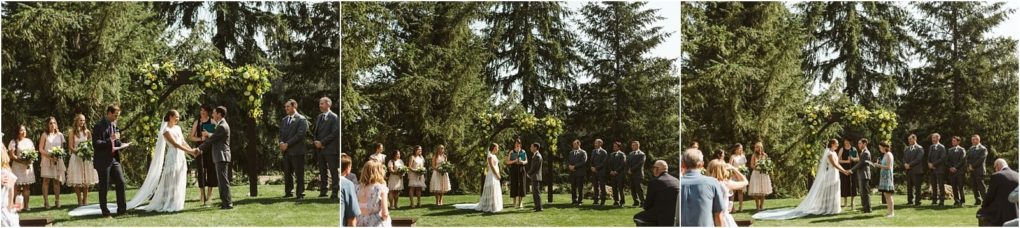 Premier snohomish & seattle wedding photographer | gsquared weddings photography a bride and groom stand under a floral arch during their snohomish outdoor wedding ceremony surrounded by bridesmaids and groomsmen with tall green trees in the background | serving snohomish seattle                   & beyond