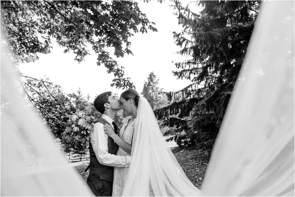 Premier snohomish & seattle wedding photographer | gsquared weddings photography a bride and groom share a kiss outdoors framed by the brides flowing veil This romantic black and white moment is captured among trees perfect for a snohomish seattle wedding or engagement session | serving snohomish seattle                   & beyond
