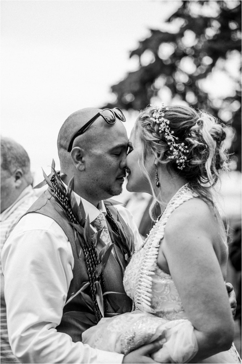 Premier snohomish & seattle wedding photographer | gsquared weddings photography a bride and groom in wedding attire stand close together touching noses and smiling gently This snohomish couple radiates joy with the bride in a floral headpiece and lei and the groom sporting sunglasses and a leafy lei | serving snohomish seattle                   & beyond