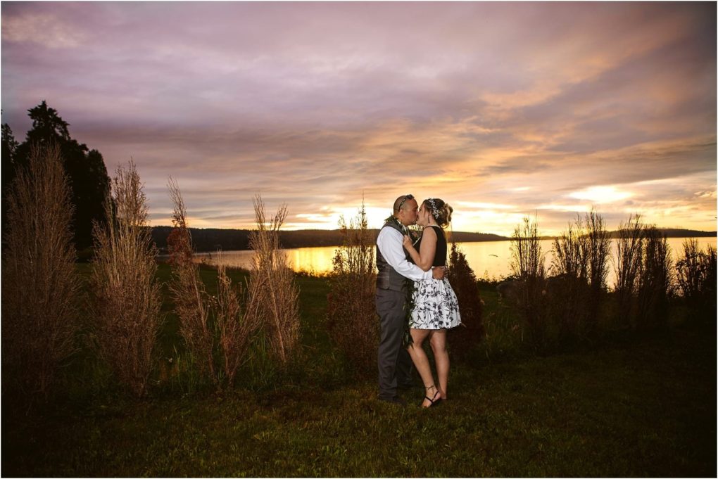 Premier snohomish & seattle wedding photographer | gsquared weddings photography a couple dressed in wedding attire embraces and kisses on grass near a lake at sunset with tall reeds and a dramatic colorful skycapturing the magic of a snohomish seattle wedding engagement | serving snohomish seattle & beyond Premier snohomish & seattle wedding photographer | gsquared weddings photography a couple dressed in wedding attire embraces and kisses on grass near a lake at sunset with tall reeds and a dramatic colorful skycapturing the magic of a snohomish seattle wedding engagement | serving snohomish seattle & beyond