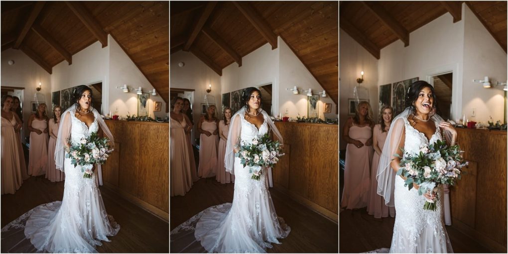 Premier snohomish & seattle wedding photographer | gsquared weddings photography a bride in a white gown holding a bouquet stands indoors reacting with joy as her bridesmaids in blush dresses watch her smiling under a wooden ceiling at a charming snohomish seattle wedding | serving snohomish seattle                   & beyond