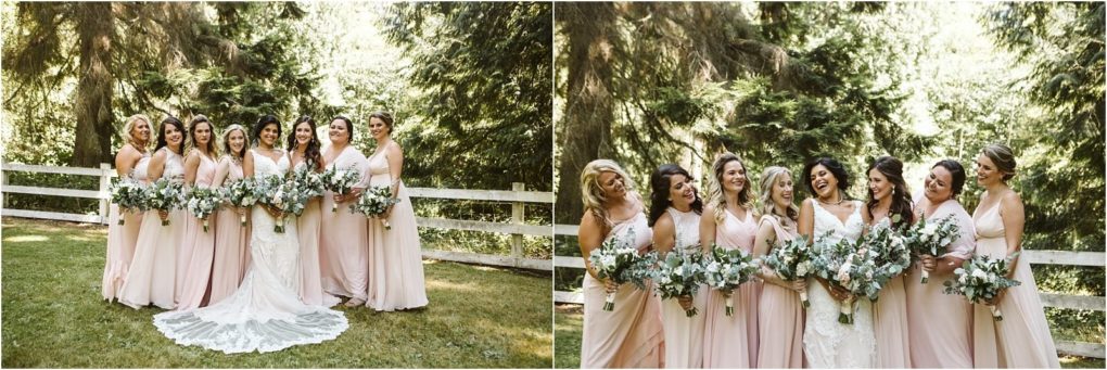 Premier snohomish & seattle wedding photographer | gsquared weddings photography a bride in a white gown stands outdoors with her bridesmaids in blush pink dresses all holding bouquets and smiling in front of a white wooden fence and tall green trees at this charming snohomish seattle wedding | serving snohomish seattle                   & beyond