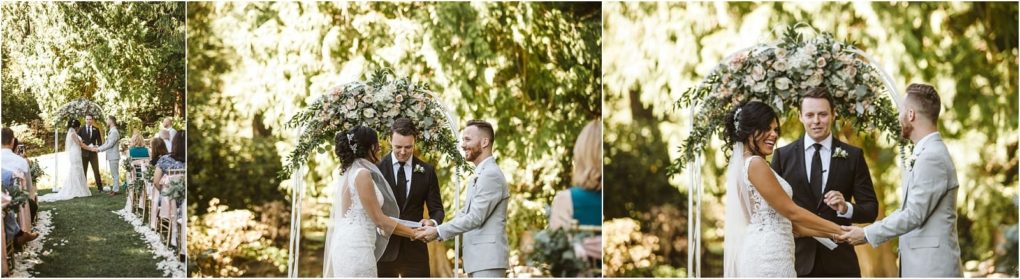 Premier snohomish & seattle wedding photographer | gsquared weddings photography a bride and groom stand hand in hand under a floral arch during their outdoor snohomish wedding ceremony smiling as an officiant guides them Guests sit on either side surrounded by greenery and sunlight | serving snohomish seattle                   & beyond