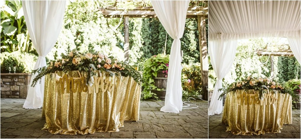 Premier snohomish & seattle wedding photographer | gsquared weddings photography a sweetheart table draped in gold sequin cloth with a mr & mrs sign and floral centerpiece perfect for a romantic snohomish seattle wedding set outdoors under a white tent with greenery and stone flooring in the background | serving snohomish seattle                   & beyond