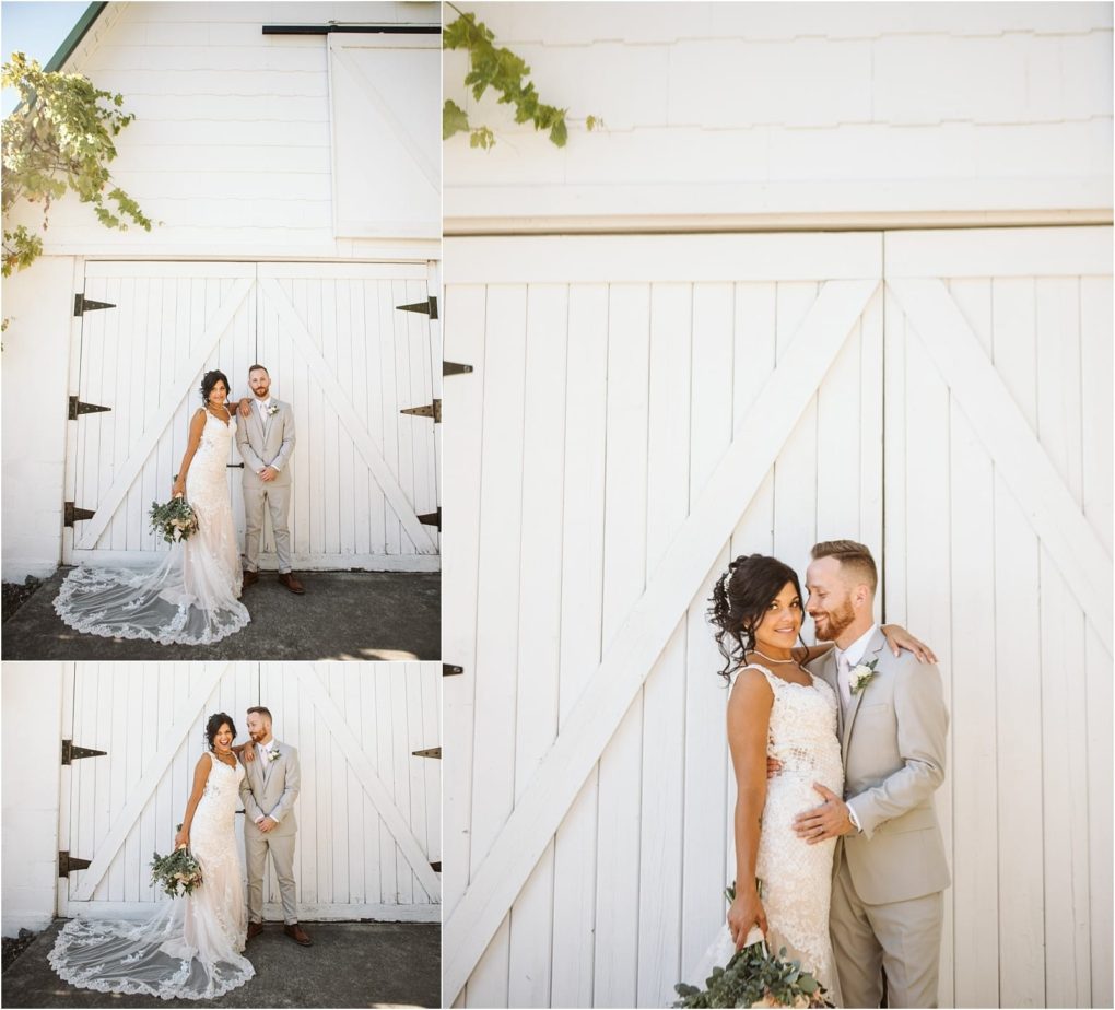 Premier snohomish & seattle wedding photographer | gsquared weddings photography a bride in a lace gown and groom in a light suit pose smiling in front of a large white barn door Greenery frames the bright outdoor setting at this charming snohomish seattle wedding | serving snohomish seattle                   & beyond