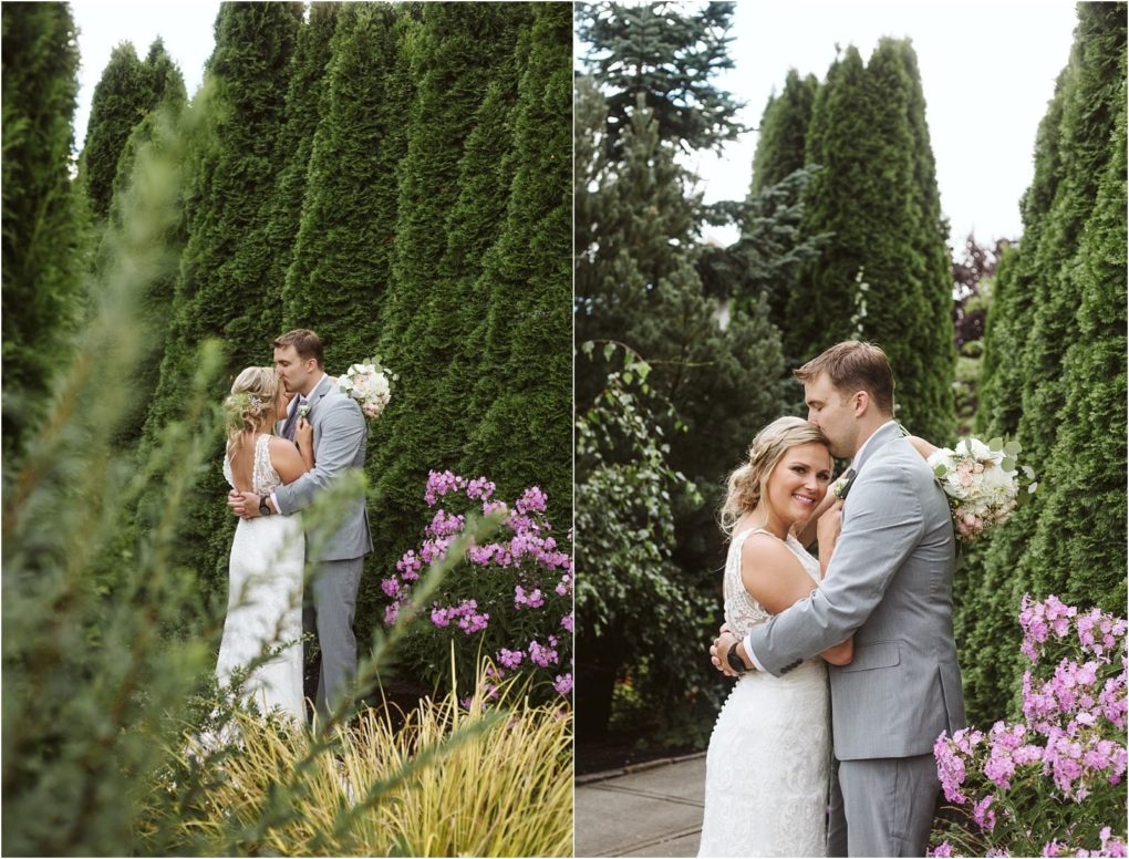 Premier snohomish & seattle wedding photographer | gsquared weddings photography a bride and groom embrace outdoors surrounded by tall green hedges and blooming purple flowers both smiling in a lace wedding gown and light gray suitcapturing a romantic snohomish seattle wedding moment | serving snohomish seattle                   & beyond