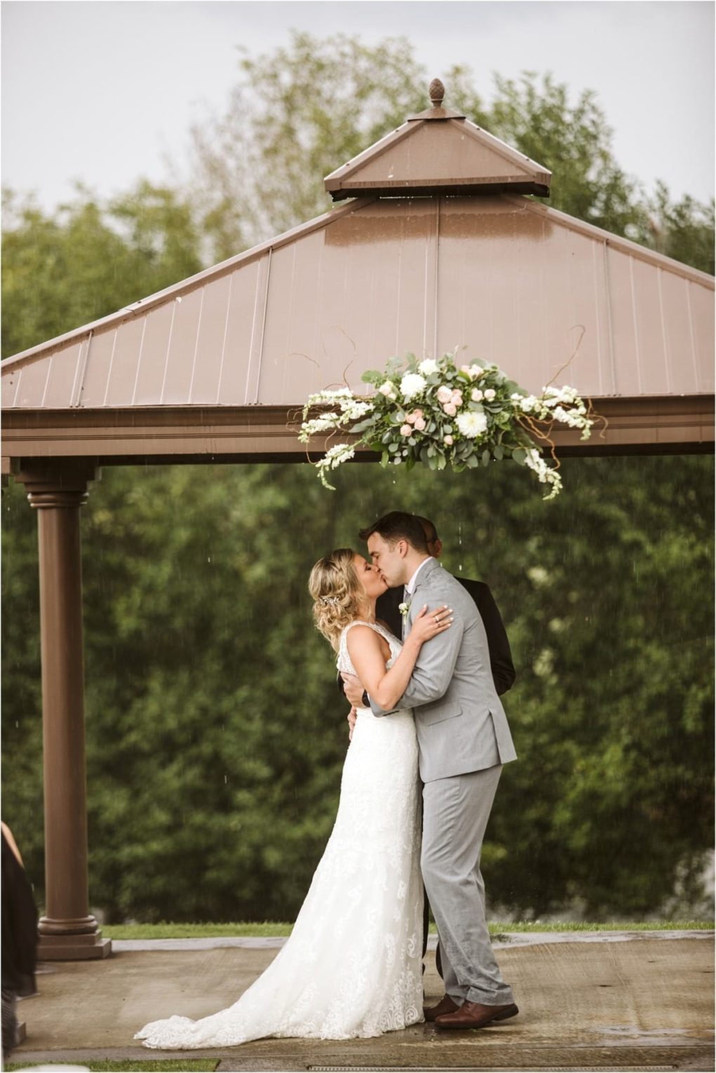 Premier snohomish & seattle wedding photographer | gsquared weddings photography a snohomish bride and groom share a kiss under a brown gazebo adorned with flowers outdoors among green trees The bride wears a white dress the groom is in a gray suit capturing a romantic seattle wedding moment | serving snohomish seattle                   & beyond
