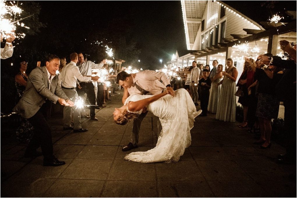 Premier snohomish & seattle wedding photographer | gsquared weddings photography a newlywed couple shares a romantic dance dip outdoors at night during their snohomish seattle wedding surrounded by guests holding sparklers and celebrating amid festive lights | serving snohomish seattle                   & beyond