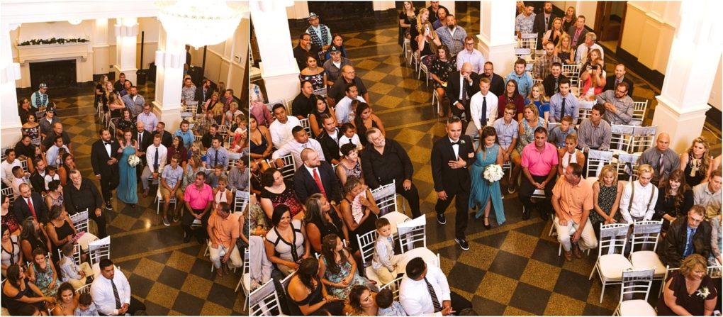 Premier snohomish & seattle wedding photographer | gsquared weddings photography a snohomish wedding ceremony seen from above with guests seated on white chairs and an aisle in the center The wedding party including the bride and groom walks down the aisle as guests watch and take photos in a bright elegant hall | serving snohomish seattle                   & beyond
