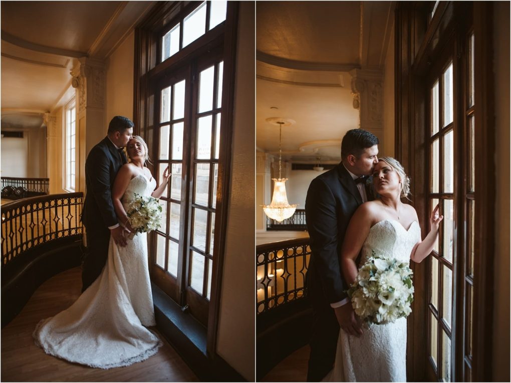 Premier snohomish & seattle wedding photographer | gsquared weddings photography a bride in a white gown holds a bouquet while standing by tall windows with her groom in a dark suit They embrace on a balcony inside an elegant building with warm lighting capturing the charm of a snohomish seattle wedding | serving snohomish seattle                   & beyond