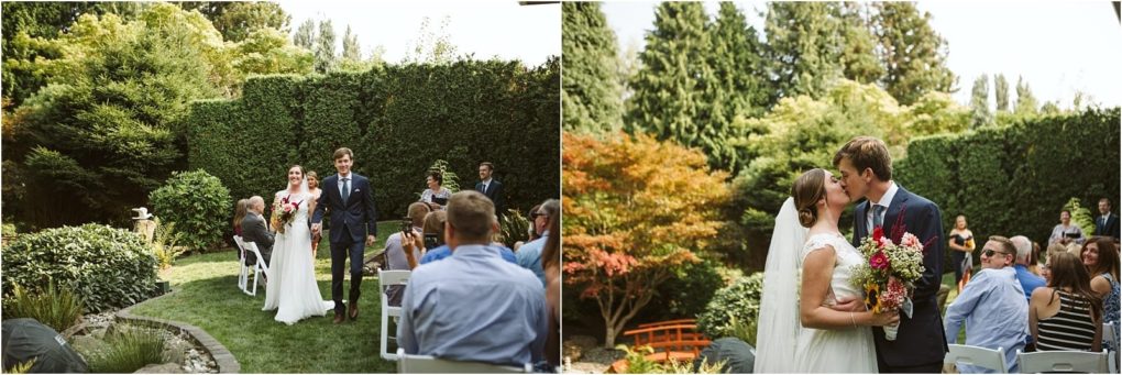 Premier snohomish & seattle wedding photographer | gsquared weddings photography a smiling bride and groom walk down an outdoor garden aisle at their snohomish wedding then share a kiss while holding a bouquet Guests seated on white chairs watch and take photos surrounded by lush trees and hedges in the sunny seattle area | serving snohomish seattle                   & beyond