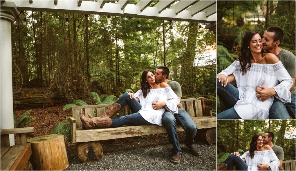 Premier snohomish & seattle wedding photographer | gsquared weddings photography a couple sits and laughs together on a rustic wooden bench in a forest near snohomish surrounded by greenery The woman wears a white off shoulder dress and brown boots while the man hugs her from behindcapturing sweet seattle engagement vibes | serving snohomish seattle                   & beyond