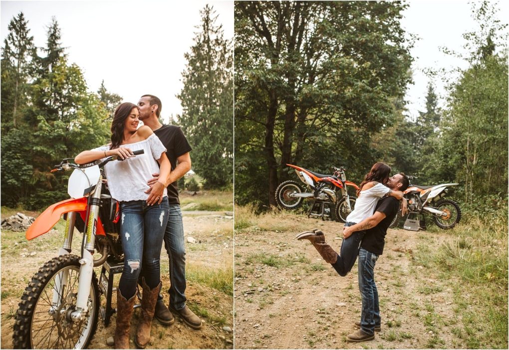Premier snohomish & seattle wedding photographer | gsquared weddings photography a couple wearing casual clothes poses with dirt bikes in a wooded area In this snohomish seattle engagement shoot the man hugs and kisses the woman as she smiles in the right he lifts her off the ground as they laugh together | serving snohomish seattle                   & beyond