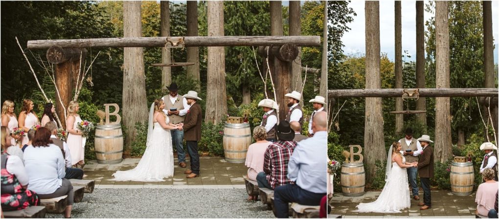 Premier snohomish & seattle wedding photographer | gsquared weddings photography a bride and groom stand beneath a rustic wooden arch outdoors in snohomish holding hands during their wedding ceremony Bridesmaids and groomsmen watch on either side with guests seated in the foreground | serving snohomish seattle                   & beyond