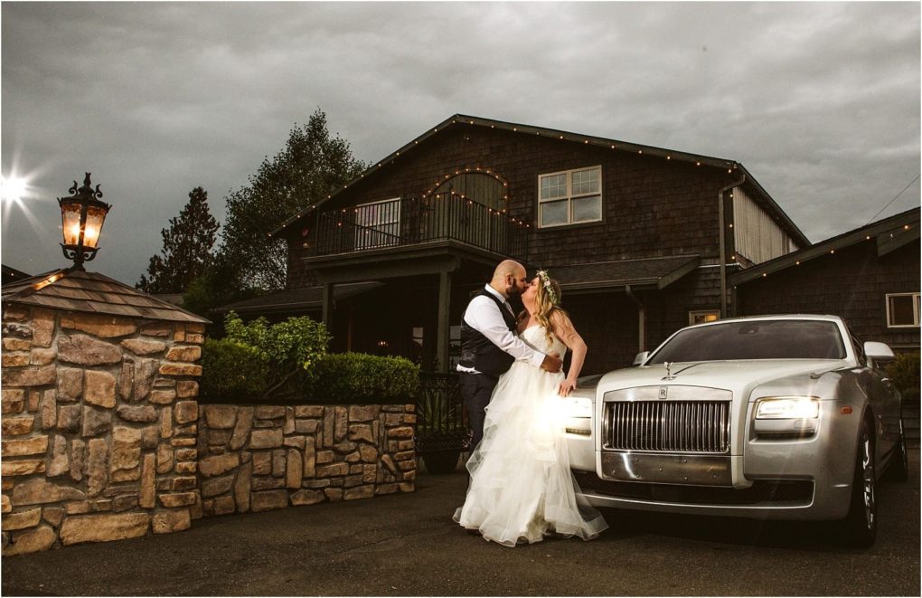 Premier snohomish & seattle wedding photographer | gsquared weddings photography a bride and groom share a kiss in front of a rolls royce parked outside a rustic building decorated with string lights under a cloudy evening sky at their snohomish seattle wedding | serving snohomish seattle                   & beyond