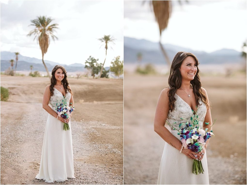 Premier snohomish & seattle wedding photographer | gsquared weddings photography a bride in a white dress holds a bouquet of purple and white flowers standing on a gravel path in a desert landscape with palm trees Perfect inspiration for your snohomish or seattle wedding engagement She has long wavy brown hair and is smiling | serving snohomish seattle                   & beyond