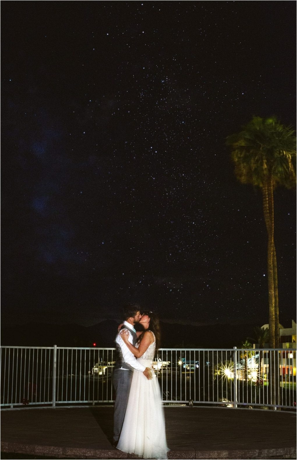 Premier snohomish & seattle wedding photographer | gsquared weddings photography a bride and groom embrace and kiss under a starry night sky standing on a patio with a white railing This romantic snohomish seattle wedding moment features a tall palm tree and distant lights in the background | serving snohomish seattle                   & beyond