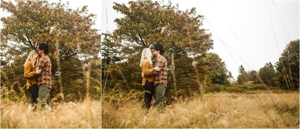 Premier snohomish & seattle wedding photographer | gsquared weddings photography a couple stands close together in a field of tall grass surrounded by autumn trees capturing a peaceful moment during their snohomish seattle engagement One wears a mustard sweater the other a plaid shirt and black hat | serving snohomish seattle                   & beyond